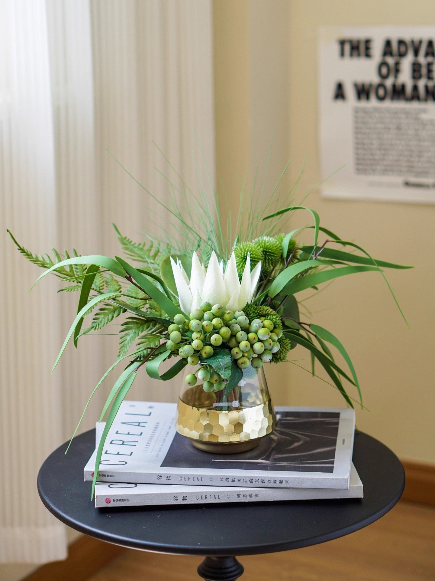 Tropical greenery floral arrangement in gold vase styled on an entryway console next to a framed artwork